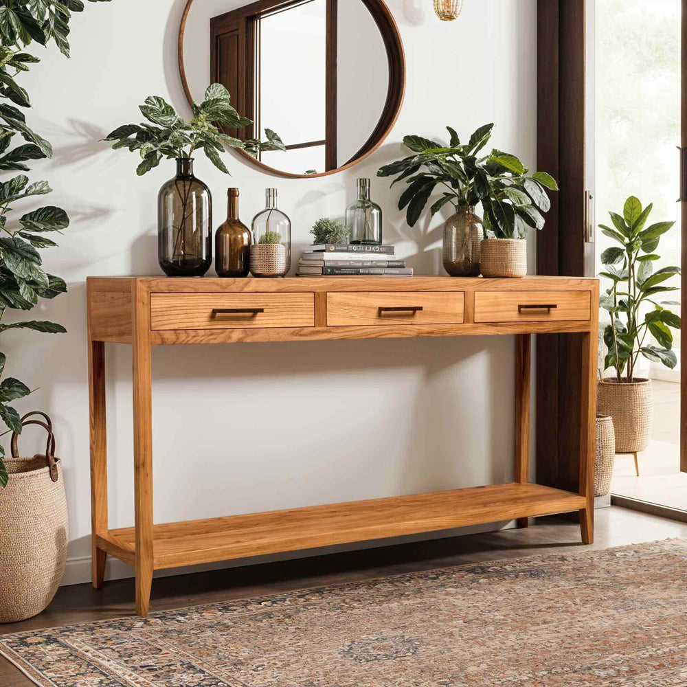 Handcrafted sustainable solid wood entryway table with drawers, styled with plants and decorative bottles in a bright room.
