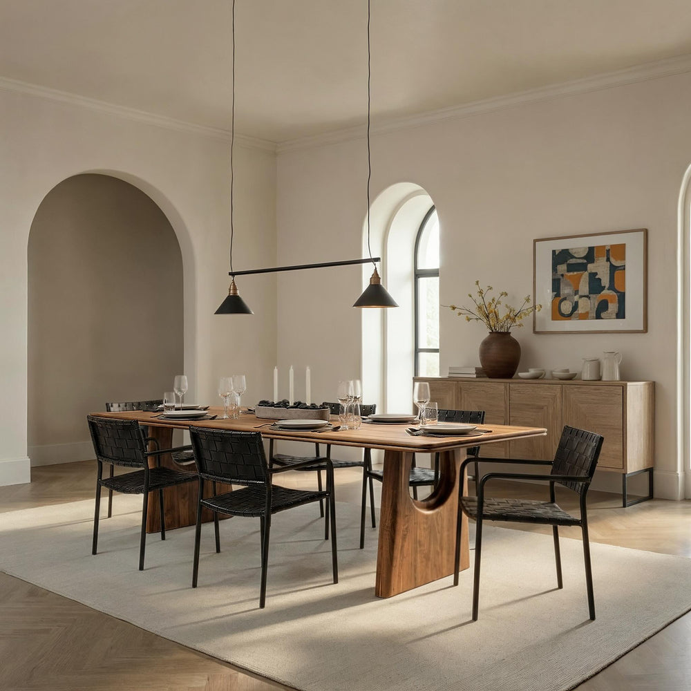 Handcrafted sustainable wood dining table with curved legs, black woven chairs, and minimalist modern decor in bright room