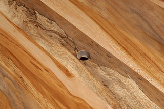 Close-up of handcrafted wooden table surface showing natural wood grain and a knot detail in sustainable lumber.